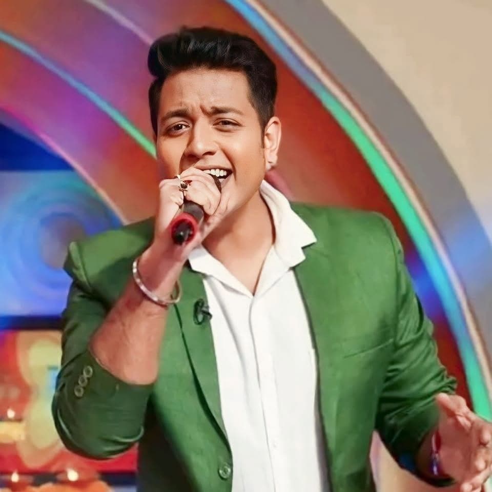 Singer Sourav Das performing live, singing into a handheld microphone in a green jacket